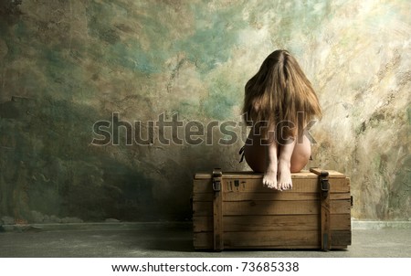 Naked  skinny woman sitting on a wooden chest