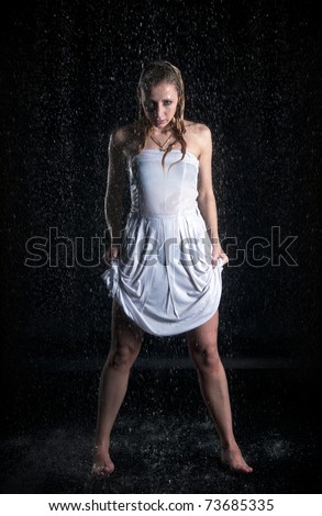 Barefoot woman in wet white dress under rain