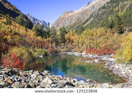 Clean mountain lake among trees and rocks of Caucasus