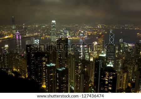 Luxury hilltop looking out over the dramatic night time neon lights and illuminated skyscrapers, crowded high-rise apartment blocks and futuristic architecture of Hong Kong Island from Victoria Peak