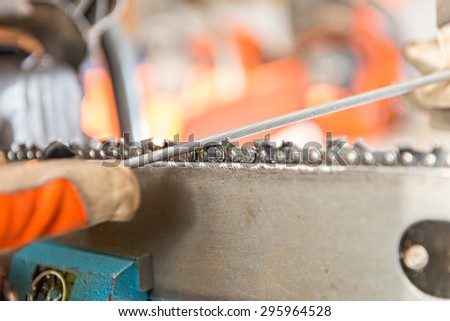 Sharpening a chainsaw\
Close up on a man sharpening a chainsaw chain with file.