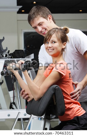 Young beautiful girl and her trainer in fitness club