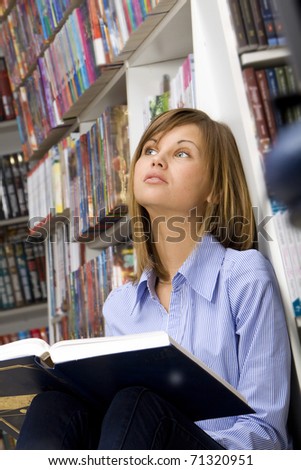 Young woman dreaming with big book in the library