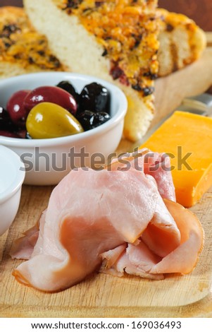 Appetizer platter with bread, cheese, meat, olives, and oil and vinegar.