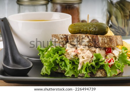 Tuna salad sandwich with lettuce on rye toast with butternut squash soup, potato chips, and a pickle