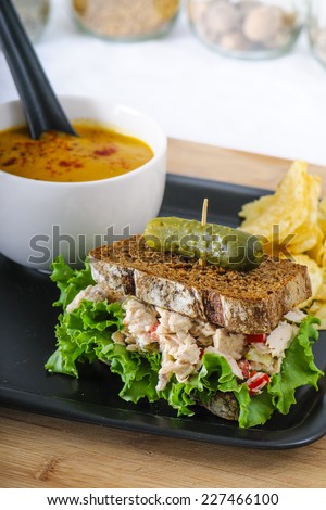 Tuna salad sandwich with lettuce on rye toast with butternut squash soup, potato chips, and a pickle