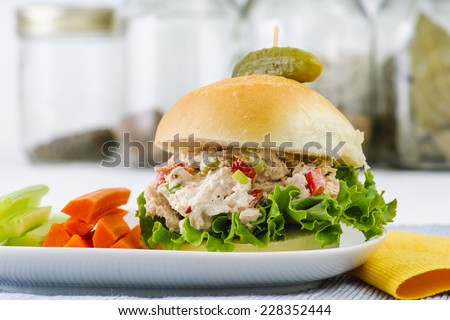 Tuna salad sandwich with lettuce on a homemade bun with healthy carrot and celery sticks and a pickle