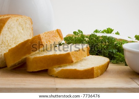 French bread on wooden cutting board with olive oil, parsley and brie cheese