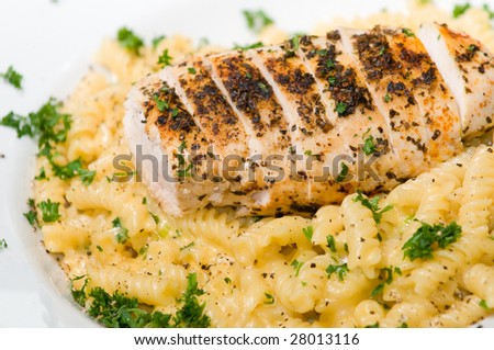 Fusilli pasta on a table with grilled chicken and cheese sauce with garlic toast and red wine
