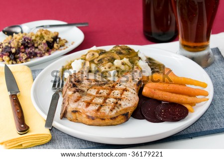Grilled pork chop with mashed potatoes, vegetables, mushroom gravy and beer