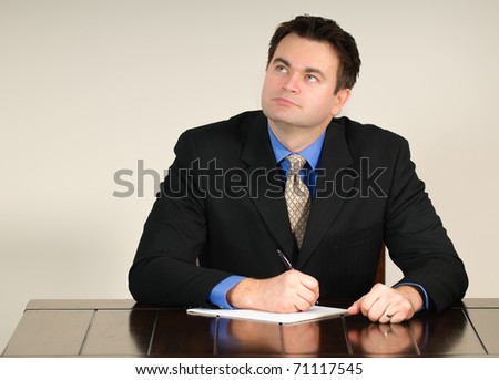 Single man in  business attire sitting at a table working and feeling frustrated