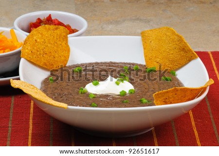 Black Bean Soup with Nacho Chips, sour cream, green onions, cheddar cheese, and salsa