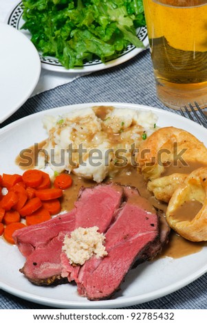 Traditional English Sunday Dinner of Roast Beef, Mashed Potatoes, Gravy, Yorkshire Pudding, Carrots, and salad.