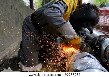 Grinder\'s working, grinding a piece of metal and making lots of sparks, no recognizable faces