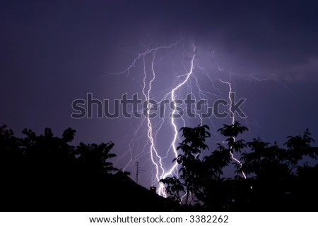 Divine light, Sky with lightning bolt and silhouette of a roof and trees, close up
