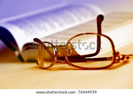 Glasses and book, extreme close-up and toned by two colors.