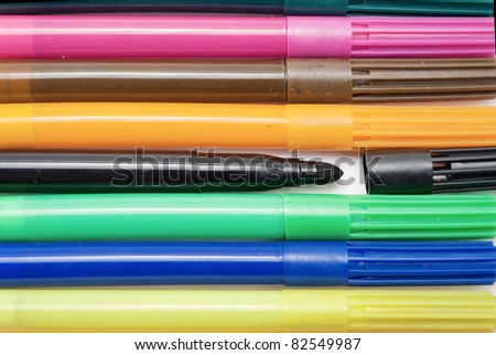 A solid background of colored markers, one with an open cap.