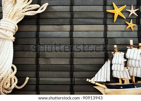 Marine themed background of sailor rope, little ship and sea stars on a wooden mat.