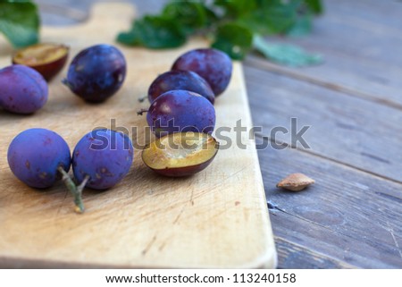 Fresh ripe plums from home garden on wooden cutting board and table in evening light