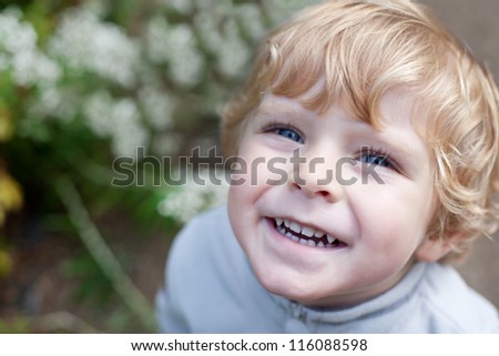 Little cute toddler boy with blond hair and blue eyes smiling