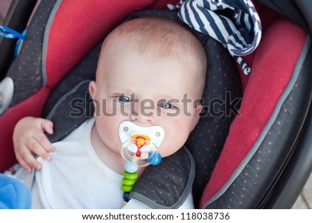 Adorable baby boy with blue eyes in safety car seat