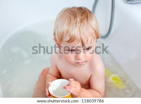Adorable little baby boy taking bath in bathtub