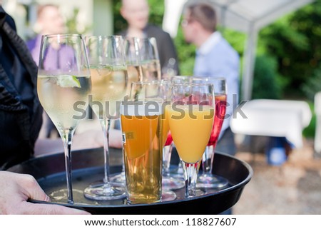 Waiter with dish of champagne, cocktails, beer and juice glasses