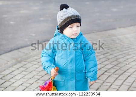 Beautiful toddler boy in blue clothes dreaming on sunny early spring day