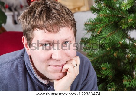 Portrait of beautiful young man smiling indoor with Christmas tree