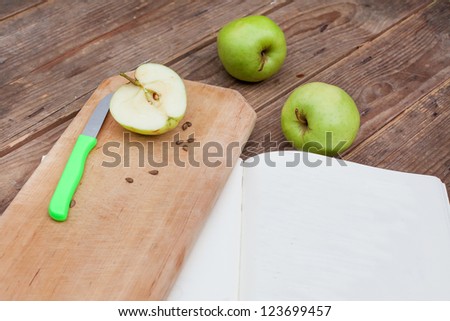 Green apples on wooden table cutted for cooking with place for recipe in book