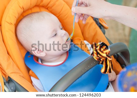Adorable baby boy first time eating meal with carrots