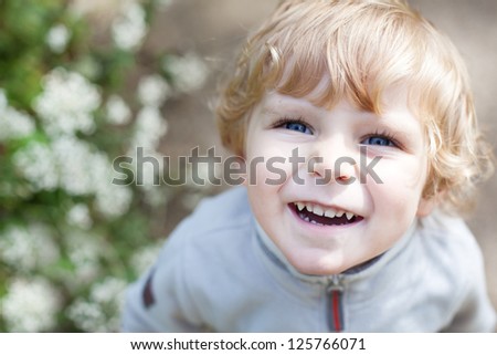 Portrait of little toddler boy with blond hairs and blue eyes smiling