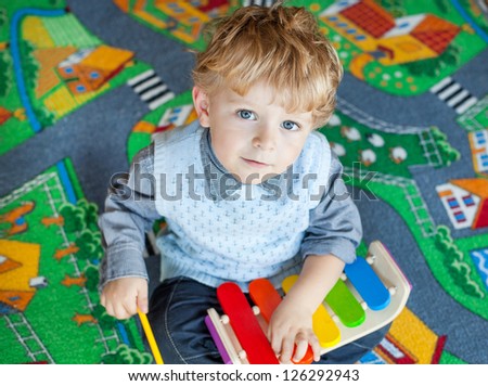 Little toddler boy playing with wooden music toy indoor