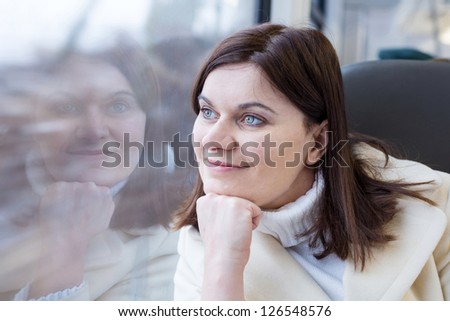 Young woman traveling by train and looking out the window outside, while it moving. travel