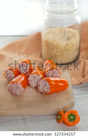 Stuffed orange pepper filled with ground meat, rice, onion on wooden cutting board