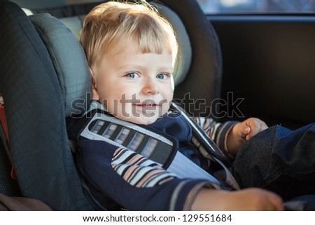 Adorable baby boy with blue eyes in safety car seat