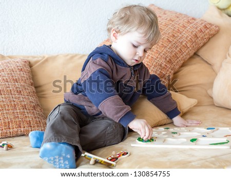 Little toddler boy playing with wooden toys indoor
