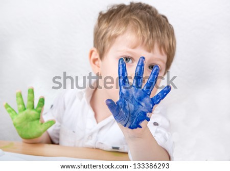 Cute little boy of three years having fun painting at home