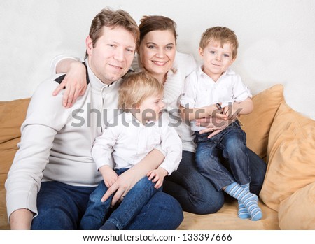 Happy family of a four having fun at home. In blue jeans and white shirts