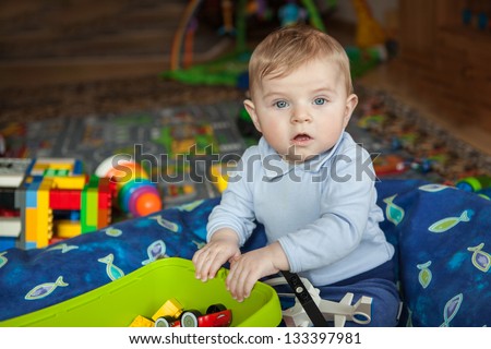 Adorable toddler with blue eyes and blond hair playing with toy indoor