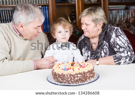 Little boy celebrating his third birthday at home with his grandmother and grandfather