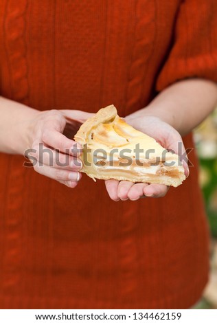 Fresh baked apple pie on wooden cutting board holding by hand of a woman