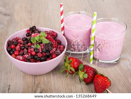 Strawberry and wild berry healthy smoothie drink. On wooden background.