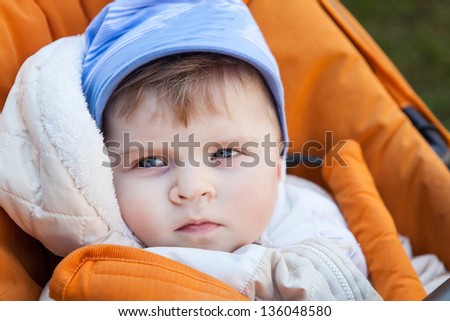 Little baby boy in spring clothes and orange pram outdoor