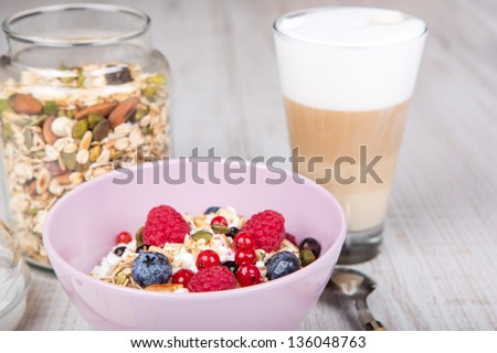 Healthy breakfast with muesli, milk, berries and coffee on textured background