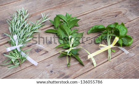 Rosemary, basil and peppermint plants in bunch on wooden table in summer