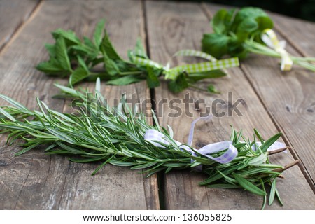 Rosemary, basil and pepermint plants in bunch on wooden table in summer