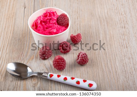 Serving of frozen creamy ice yoghurt  with whole fresh raspberries and vintage spoon