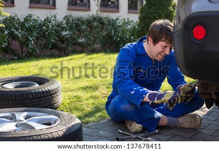 Young man changing wheel on car with pneumatic wrench