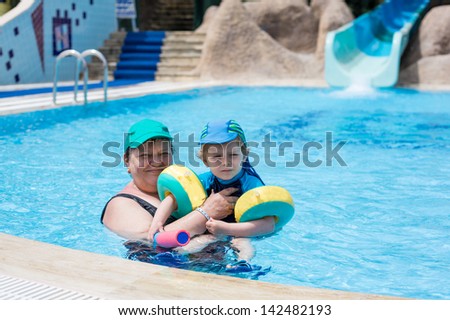 Grandmother and grandson swimming together in the pool. Outdoor, summer.